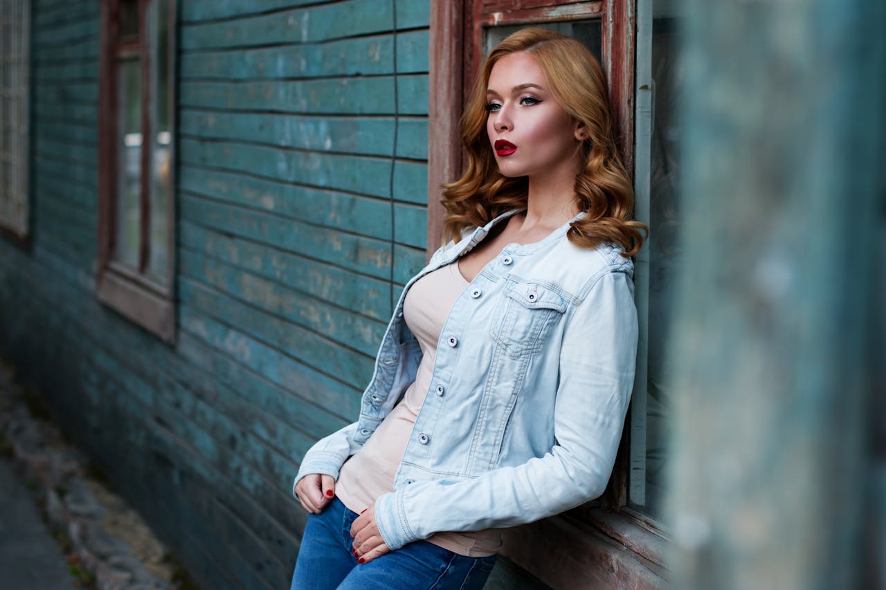 Stylish woman with red lipstick poses against a rustic wooden wall, exuding urban charm.