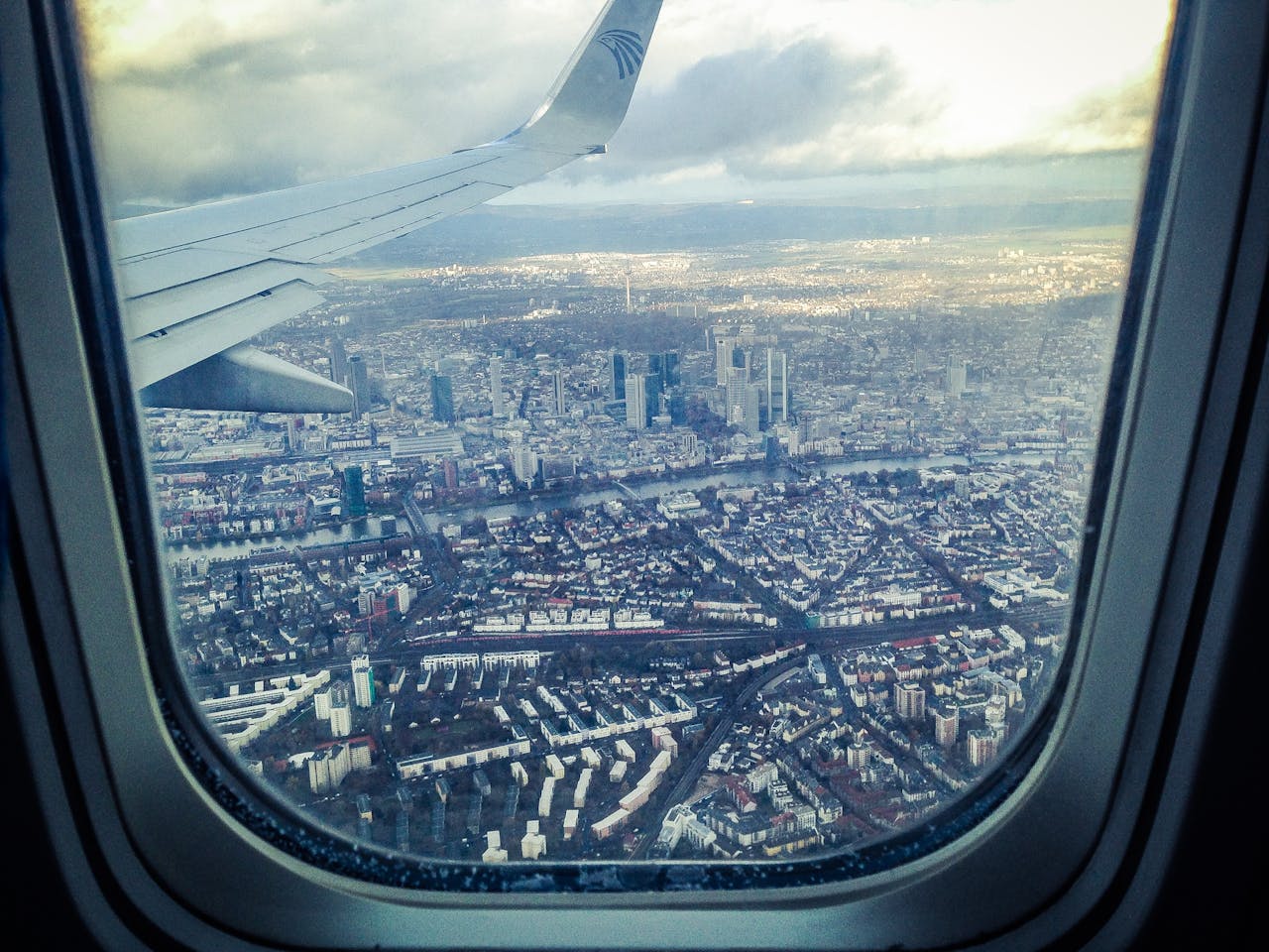 Stunning aerial view of Frankfurt am Main through an airplane window, showcasing the city's skyline and architecture.
